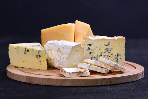 Foto verschiedene gourmet-käsesorten gorgonzola schafe käseparmesan und dor blue auf einem hölzernen schneidebrett