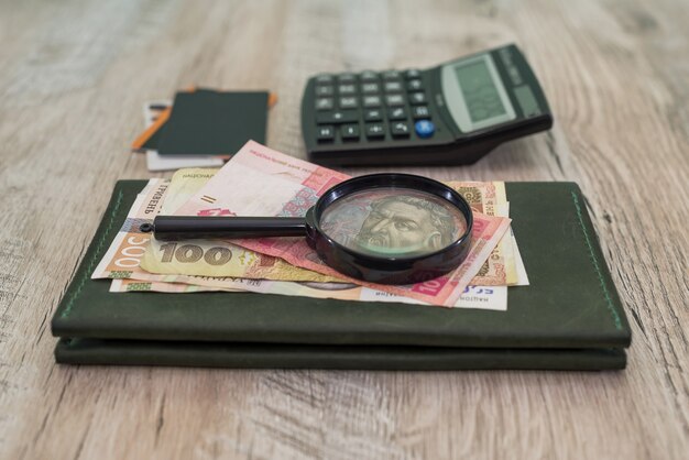 Verschiedene Griwna, Kreditkarten, Brieftasche, Taschenrechner, Lupe auf einem Holztisch. Finanzkonzept.