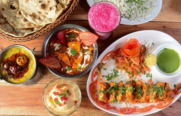 Verschiedene indische Speisen auf Holzhintergrund Paneer tikka dal tadkajeera riceroti Gerichte und Vorspeisen der indischen Küche