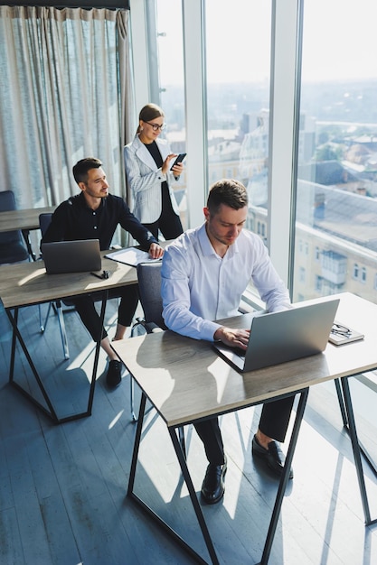 Verschiedene internationale Geschäftsleute, die mit Laptops an einem Projekt am Tisch arbeiten Multirassisches Team diskutiert die Projektstrategie, während sie in einem modernen Büro zusammenarbeiten