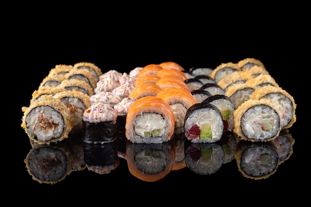 Verschiedene japanische Sushi-Rollen auf schwarzem Hintergrund mit Reflexion gesetzt. Sushi-Menü. Sushi-Rollen der japanischen Küche im Restaurant, Nahaufnahme, selektiver Fokus