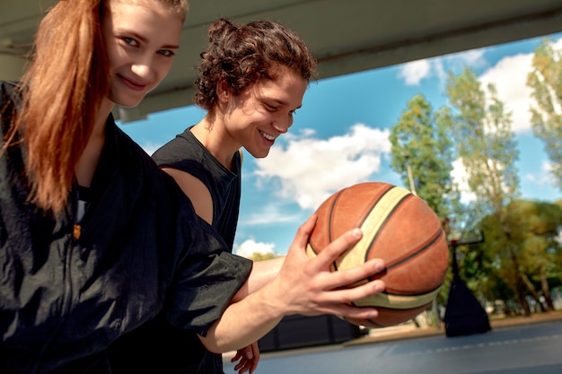 Verschiedene Jungen und Mädchen spielen an einem sonnigen Tag Basketball