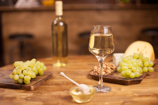 Verschiedene Käsesorten mit einer Flasche und einem Glas Wein auf gelbem Hintergrund. Köstliche frische Trauben. Leckerer Honig.