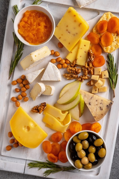 Verschiedene Käsesorten mit Nüssen, Birnen, getrockneten Aprikosen und Rosmarin.