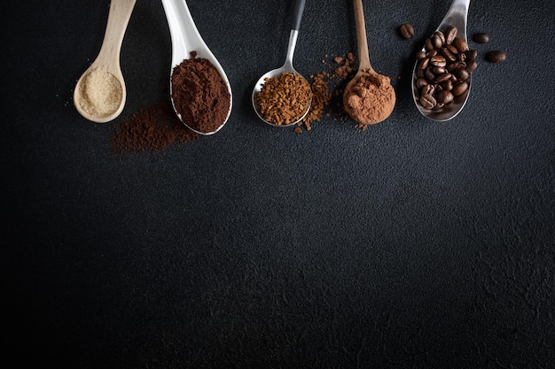 Verschiedene Kaffeearten auf Löffeln auf dunklem Hintergrund Kaffeekonzept von oben