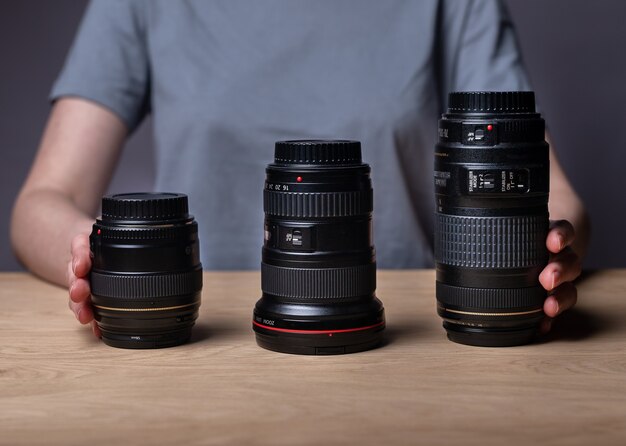 Verschiedene Kameraobjektive auf Holztisch. 85mm, 35mm und 300mm. Verschiedene moderne Digitalobjektive in verschiedenen Größen.