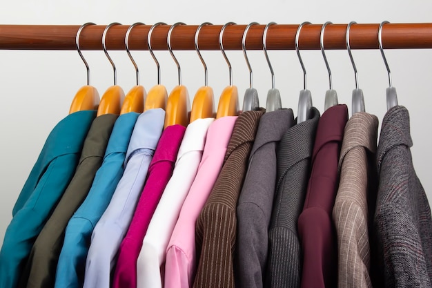 Verschiedene klassische Jacken und Hemden für Frauenbüros hängen an einem Kleiderbügel, um Kleidung aufzubewahren