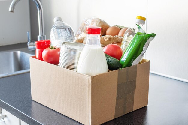 Verschiedene Lebensmittelflaschen mit Ölmilch und frischem Wassergemüse in einem Karton