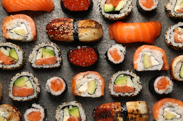 Verschiedene leckere Sushi-Rollen auf einem grauen Tisch lagen flach