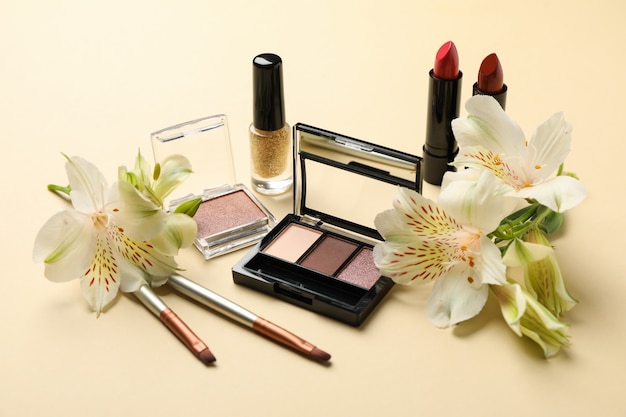 Verschiedene Make-up-Kosmetik und Blumen auf beigem Hintergrund