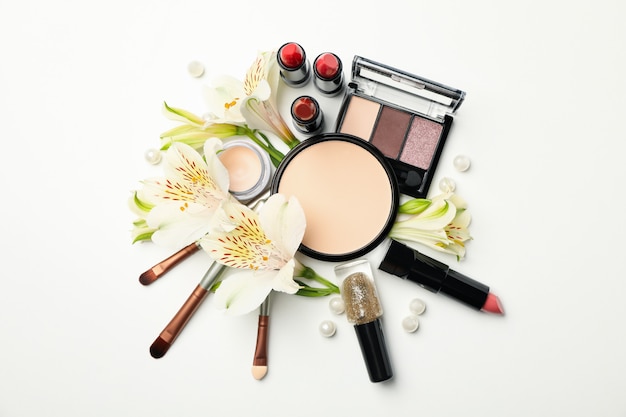 Verschiedene Make-up-Kosmetik und Blumen auf weißem Hintergrund. Weibliches Zubehör