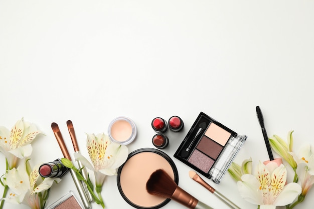 Verschiedene Make-up-Kosmetik und Blumen auf weißem Hintergrund. Weibliches Zubehör