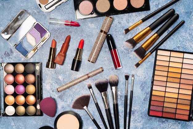 Verschiedene Make-up-Produkte, Pinsel auf blauem Hintergrund