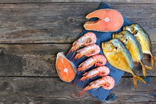 Verschiedene Meeresfrüchte: Fisch, Garnelen auf altem Holzhintergrund. Draufsicht. Flach liegen.