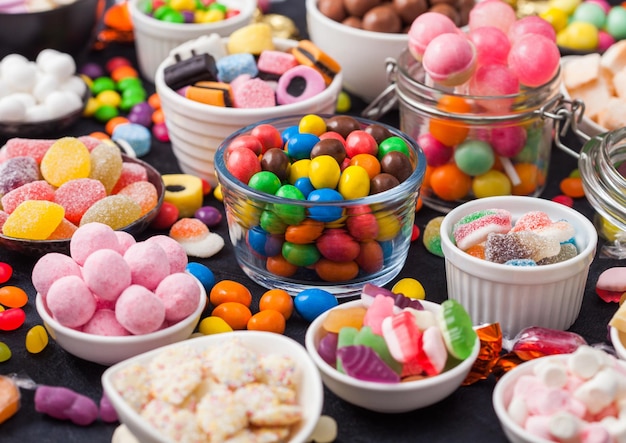 Verschiedene Milchschokoladen- und Geleezucker-Gummibonbons und Bonbons auf Schwarz Beste Snacks für Kinderpartys