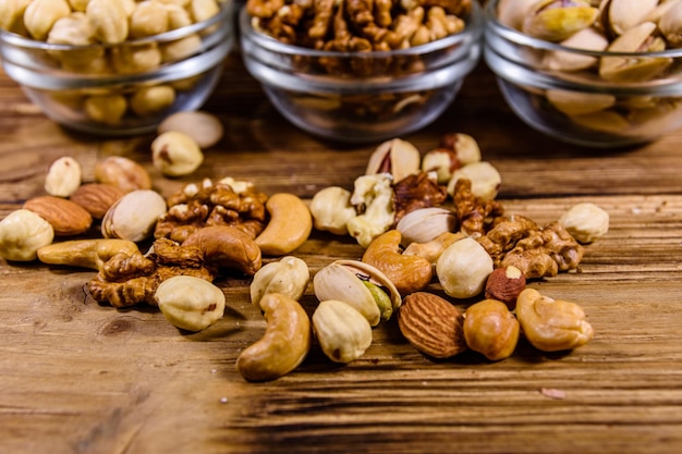 Verschiedene Nüsse Mandel Cashew Haselnuss Pistazie Walnuss in Glasschalen auf einem Holztisch Vegetarische Mahlzeit Konzept für gesunde Ernährung