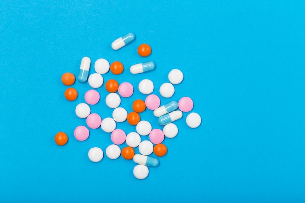 Verschiedene pharmazeutische Medizinpillen, Tabletten und Kapseln auf blauem Hintergrund. Freiraum. Gesundheitskonzept.
