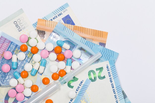 Verschiedene pharmazeutische Medizinpillen, Tabletten und Spritzen auf EU-Euro auf weißem Hintergrund. Gesundheitskonzept. Krise. Geld. Freiraum. Speicherplatz kopieren.