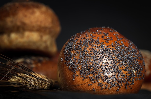 Verschiedene runde hausgemachte Brioche-Brötchen mit Samen auf dunklem Hintergrund mit kontrastreichem Licht. Isoliert