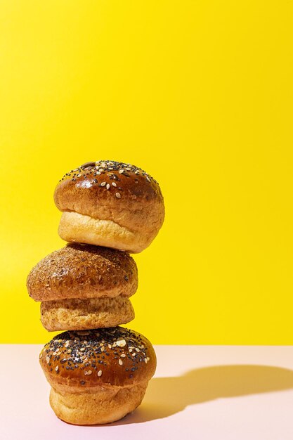 Verschiedene runde hausgemachte Brioche-Brötchen mit Samen auf einem bunten Hintergrund mit kontrastreichem Licht