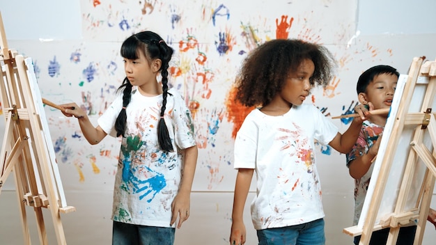 Verschiedene Schüler malten oder zeichneten Leinwand an der gefärbten Wand in der Kunststunde Erudition