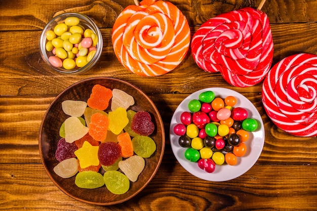 Verschiedene süße Bonbons auf rustikalem Holztisch. Ansicht von oben