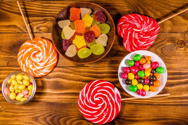 Verschiedene süße Bonbons auf rustikalem Holztisch. Ansicht von oben