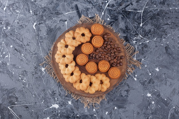 Verschiedene süße Kekse mit Aromakaffeebohnen auf einem Holzstück.