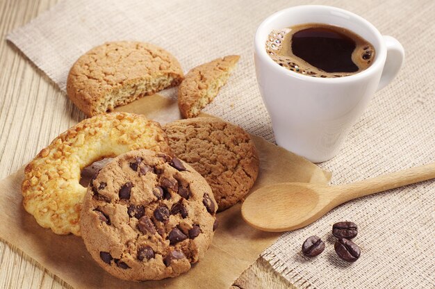 Verschiedene süße Kekse und eine Tasse heißen Kaffee auf Holztisch