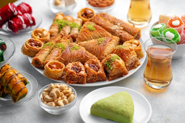 Verschiedene türkische Süßigkeiten und eine Tasse Tee auf weißem strukturiertem Hintergrund