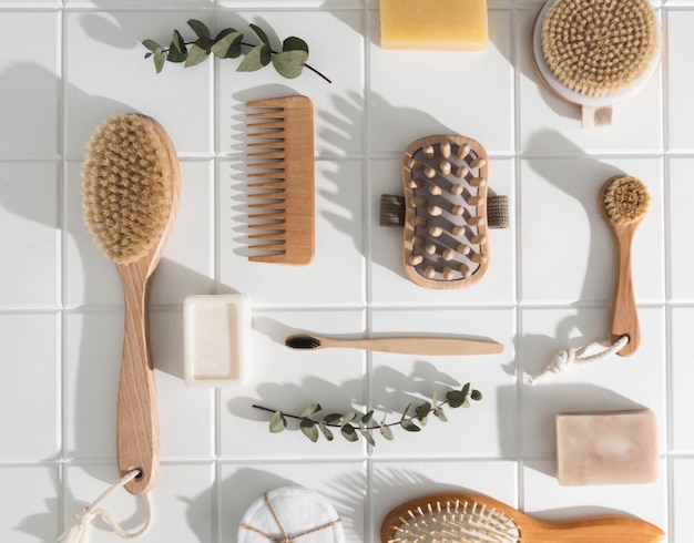 Verschiedene umweltfreundliche Badezimmerartikel für Gesichts- und Körperpflege und Hygiene auf weißem Fliesengrund.