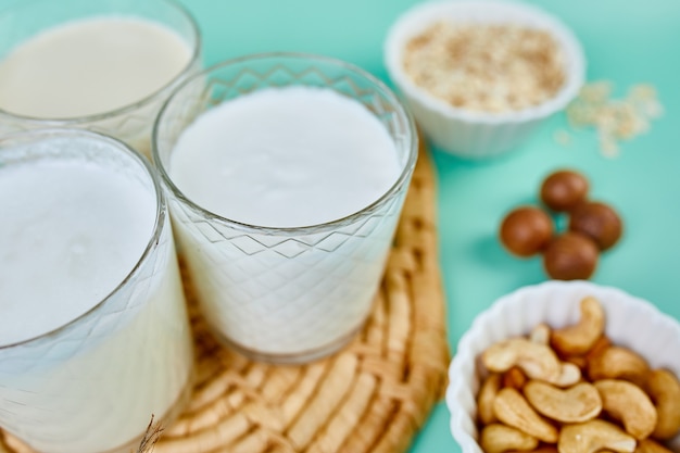 Verschiedene vegane Pflanzenmilch und Zutaten, milchfreie Milch, alternative Arten von veganer Milch in Gläsern auf blauem Hintergrund mit Kopierraum