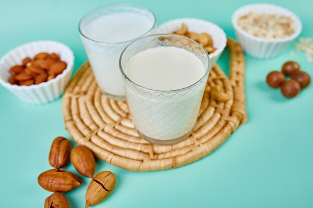 Verschiedene vegane Pflanzenmilch und Zutaten, milchfreie Milch, alternative Arten von veganer Milch in Gläsern auf blauem Hintergrund mit Kopierraum