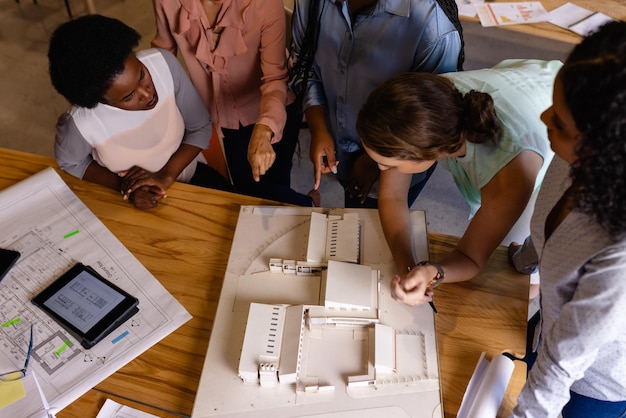 Verschiedene weibliche Architekten diskutieren über Modelle und Blaupausen in einem casual Office-Meeting. Casual Office, Teamwork, Business, Lifestyle, kreative Arbeit, Design und Arbeit, unverändert.