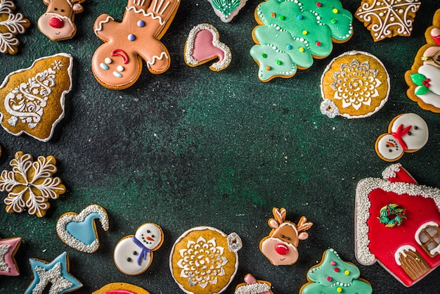 Verschiedene zuckerglasierte festliche Weihnachten und Neujahr süße Plätzchen Hintergrundkarte. Einfaches Muster mit hausgemachten Weihnachtsplätzchen auf dunkelgrünem Hintergrund