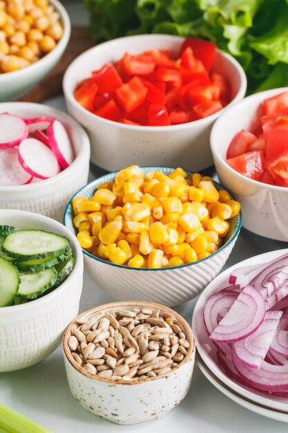 Verschiedene Zutaten für gesunden vegetarischen Salat in verschiedenen Portionsschalen auf einem Tisch Das Konzept von Fitness und veganer Ernährung