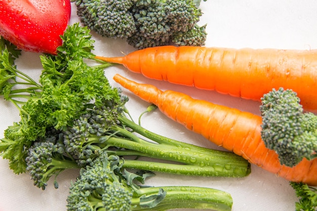 Verschiedenes Gemüse und frische Kräuter mit Wassertropfen auf dem weißen Tisch vegetarische echte Komposition