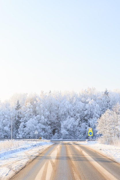 Verschneite Winterstraße durch verschneite Felder und Wälder