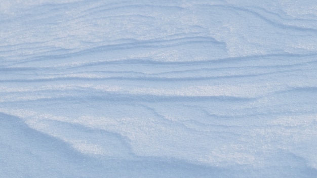 Verschneiter Hintergrund, schneebedeckte Erdoberfläche nach einem Schneesturm am Morgen im Sonnenlicht mit deutlichen Schneeschichten
