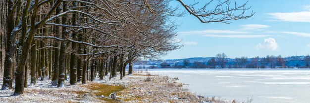 Verschneiter Wald in der Nähe des Flusses mit Eis und Schnee bedeckt