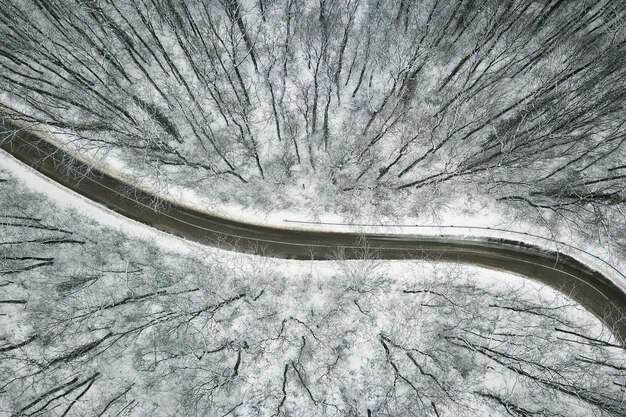 Verschneiter Wald mit einer Straße. Luftaufnahme.