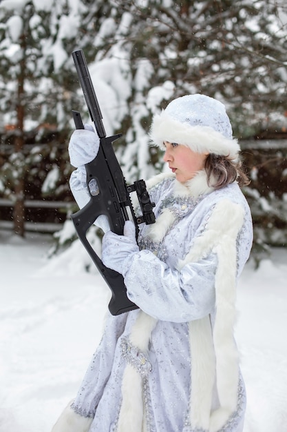 Verschneiter Winter. Eine junge Frau in einem Schneewittchen-Kostüm hält ein Gewehr.