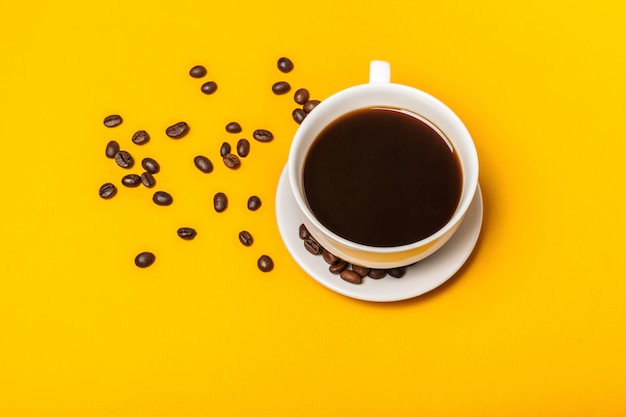 Verschüttete Kaffeebohnen auf einem hellen gelben Hintergrund