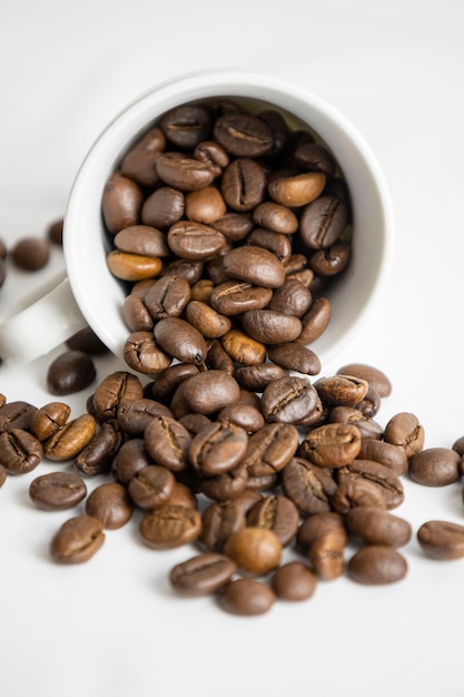 Verschüttete Kaffeebohnen aus einer Tasse Weißer Hintergrund