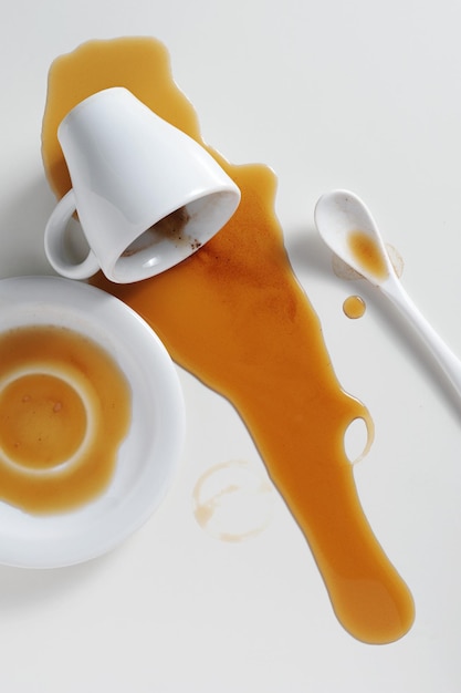 Verschüttete Tasse Kaffee auf weißem Tisch, aufgenommen von oben