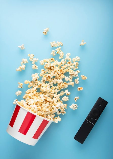 Verschüttetes Popcorn auf einem blauen Hintergrund mit Fernsehapparat entfernen.