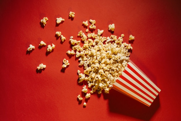 Verschüttetes Popcorn auf rotem Hintergrund, Kino, Filme und Unterhaltungskonzept