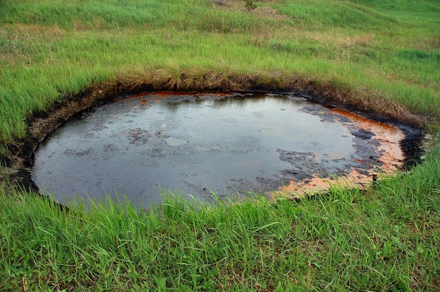 Verschüttetes Rohöl auf der Bodenoberfläche Krater des Vulkans