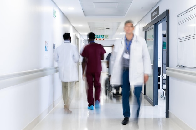 Verschwommene Bewegungen verschiedener Ärzte und medizinisches Personal im belebten Krankenhauskorridor. Krankenhaus, medizinische und Gesundheitsdienste.
