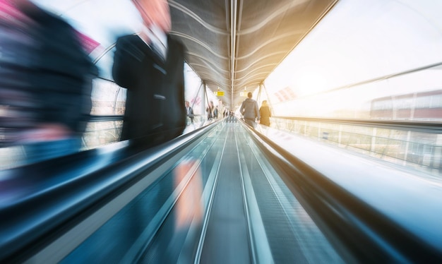 Foto verschwommene geschäftspendler, die auf einer rolltreppe in einem flughafen hetzen. ideal für webseiten und zeitschriftenlayouts